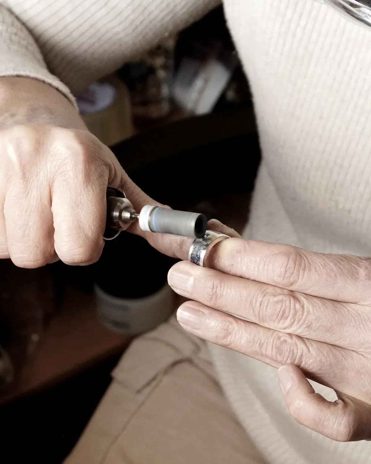 Las manos sujetando una pieza mientras la pulen con el micromotor.