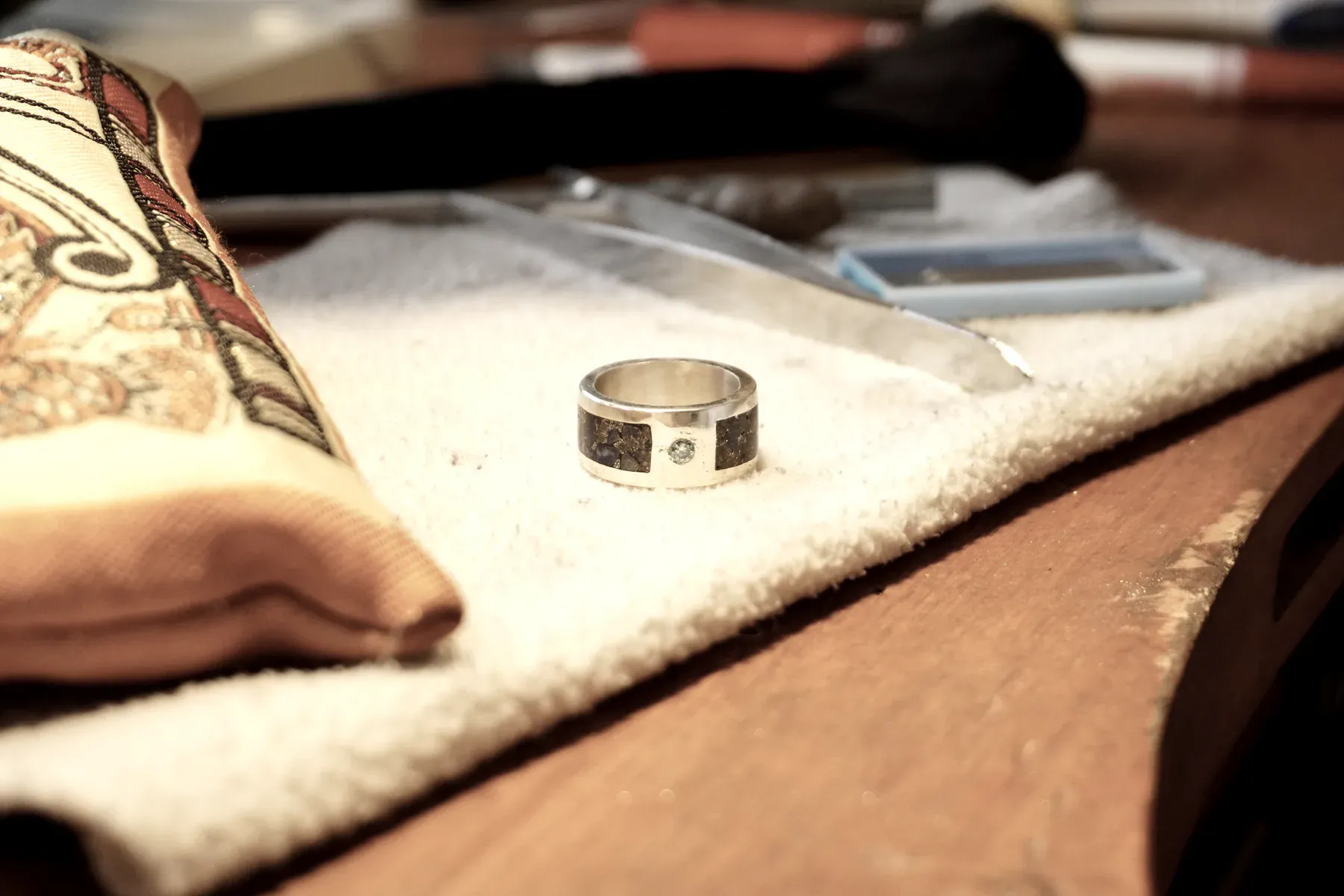 Un anillo terminado con una piedra celeste, sobre el paño del banco.